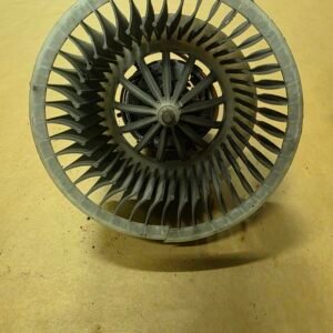 Circular turbine impeller with numerous curved blades, viewed from above on a workshop floor.