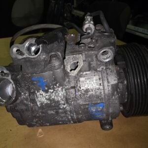 Dirty automotive alternator/dynamo with belt pulley and wiring, labeled DENSO, on a workshop surface