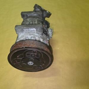 Close-up of a rusty automotive pulley and mounting housing on a yellow background.