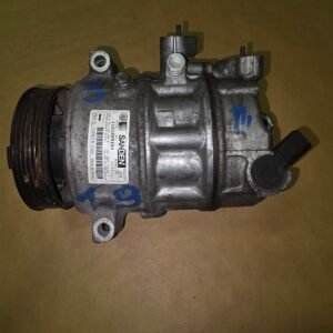 Automotive air conditioning compressor with a belt pulley on the left and mounting lugs on a brown background.